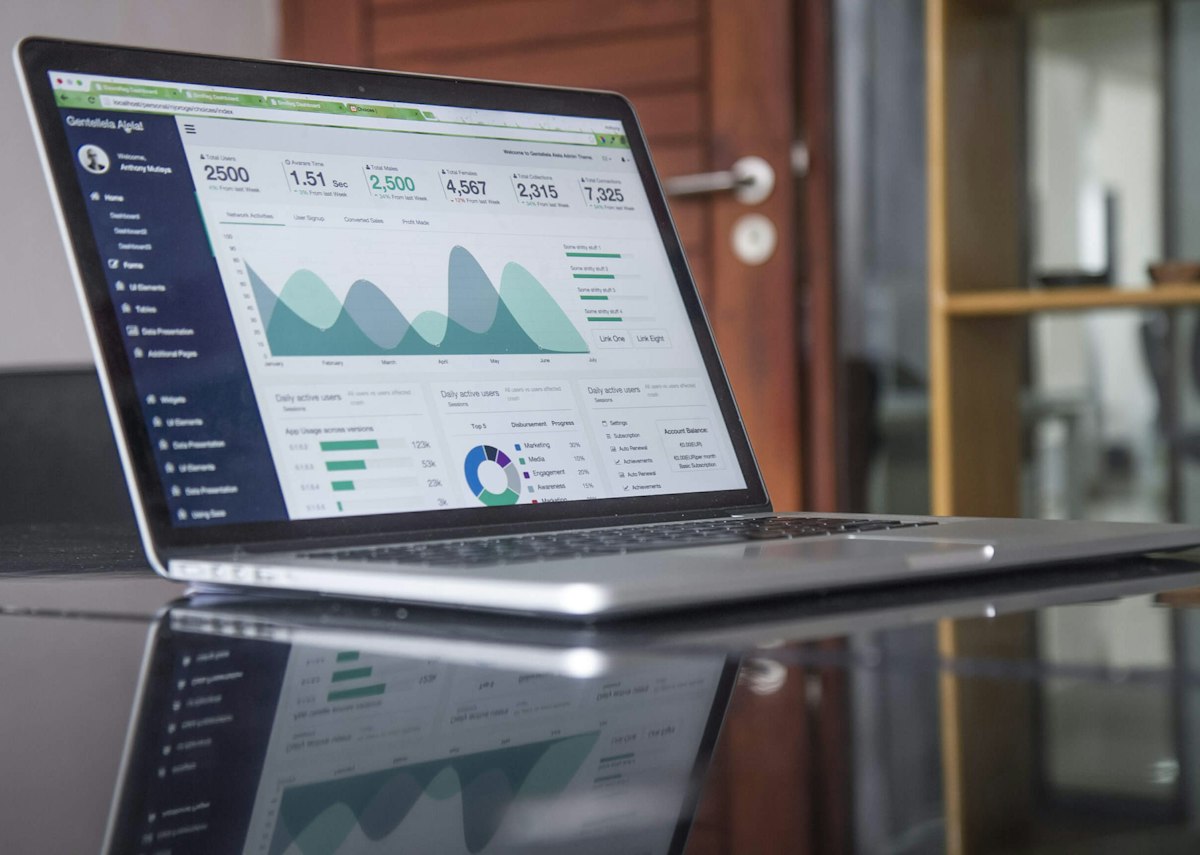 Laptop mit Tabellen und Analysegrafiken auf einem Schreibtisch